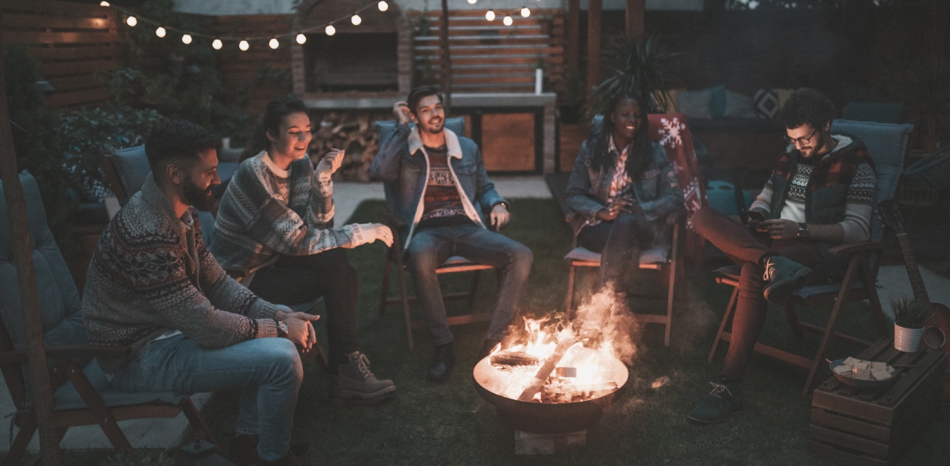 five friends sitting by a bonfire at night