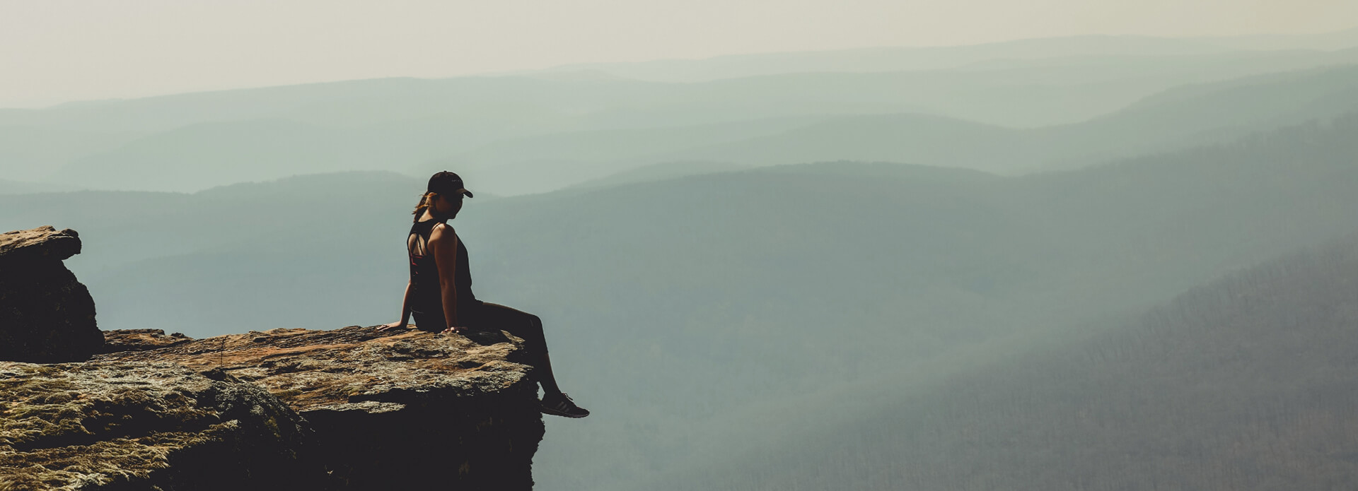 woman sitting on edge of a cliff overlooking the scenery